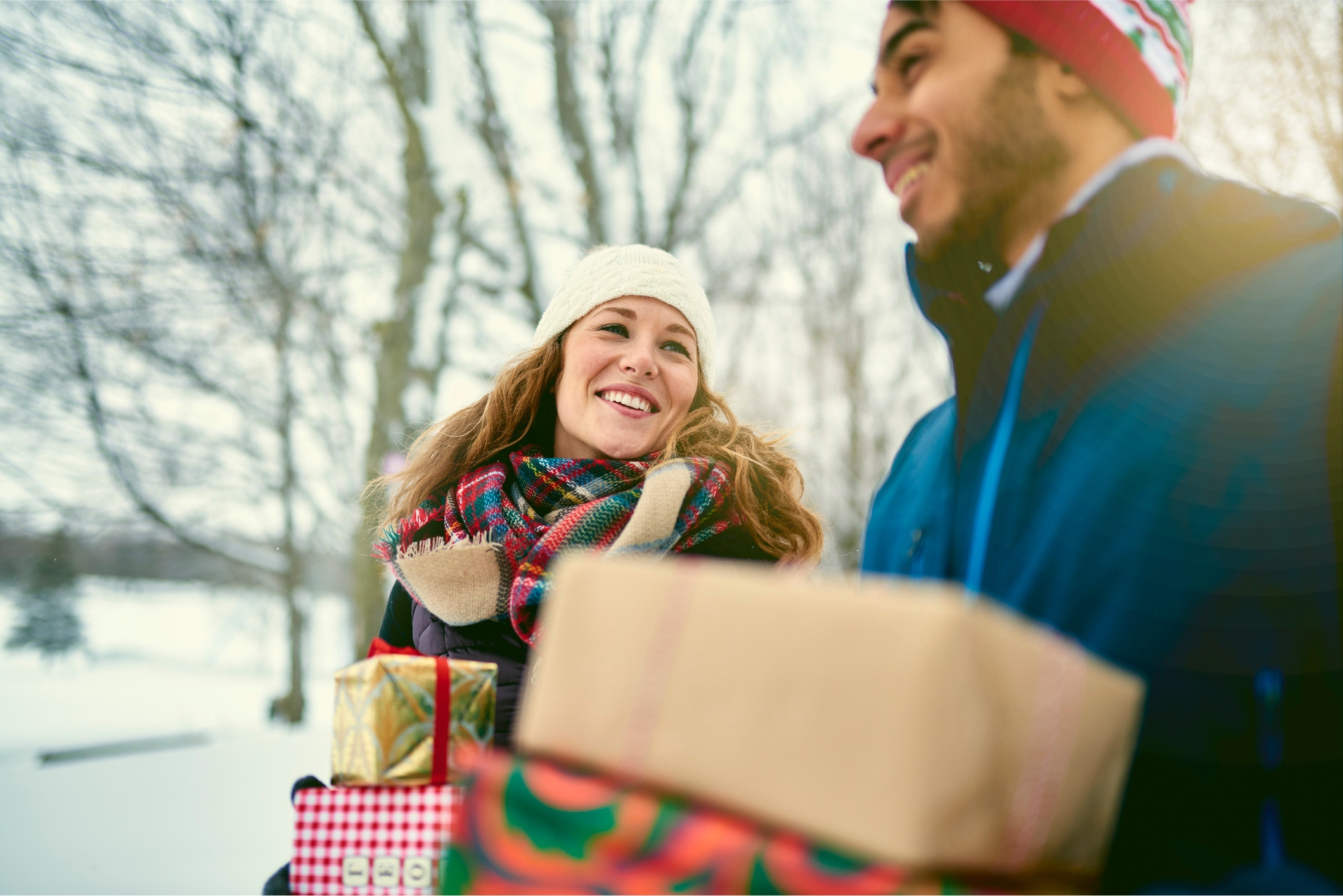 A pair of young adults carrying holiday gifts